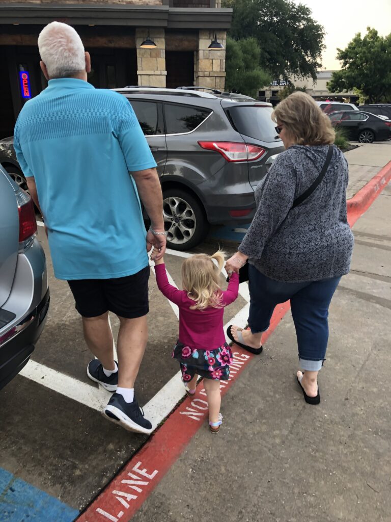 grandparents holding grand daugther's hand