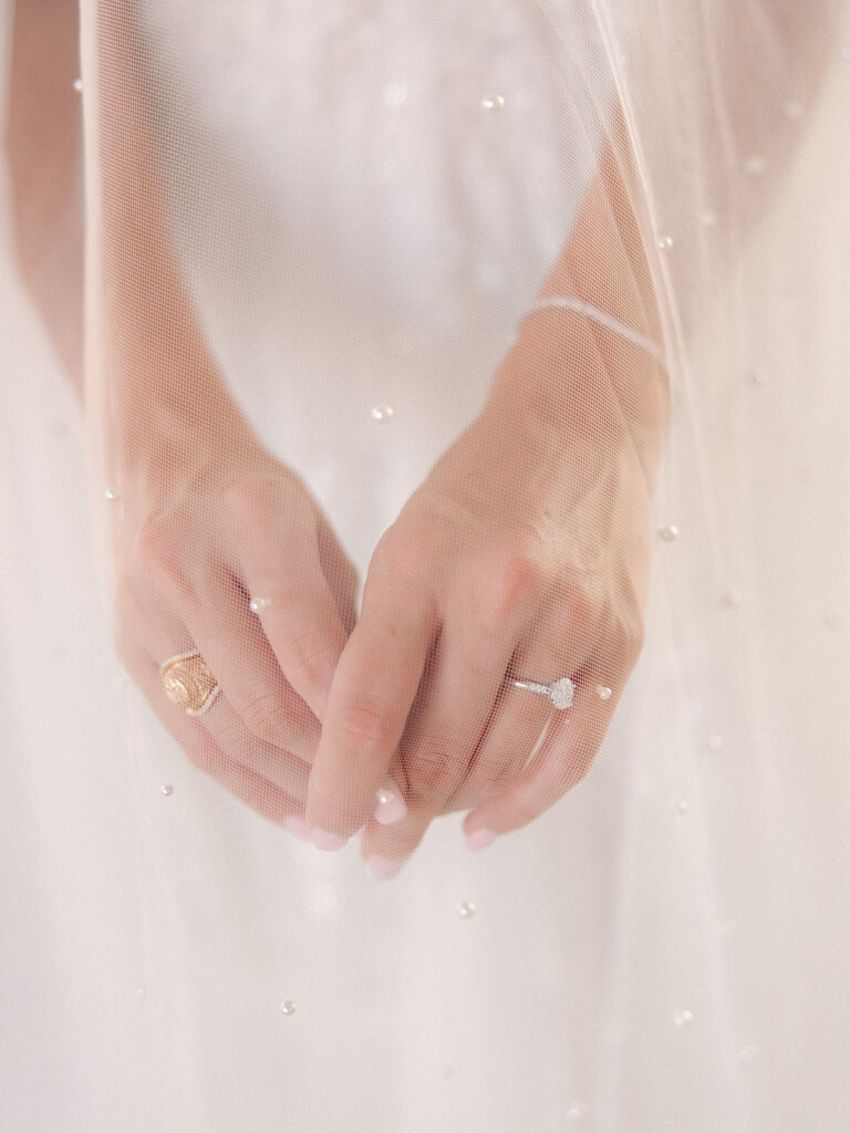 close up of hands and ring under veil