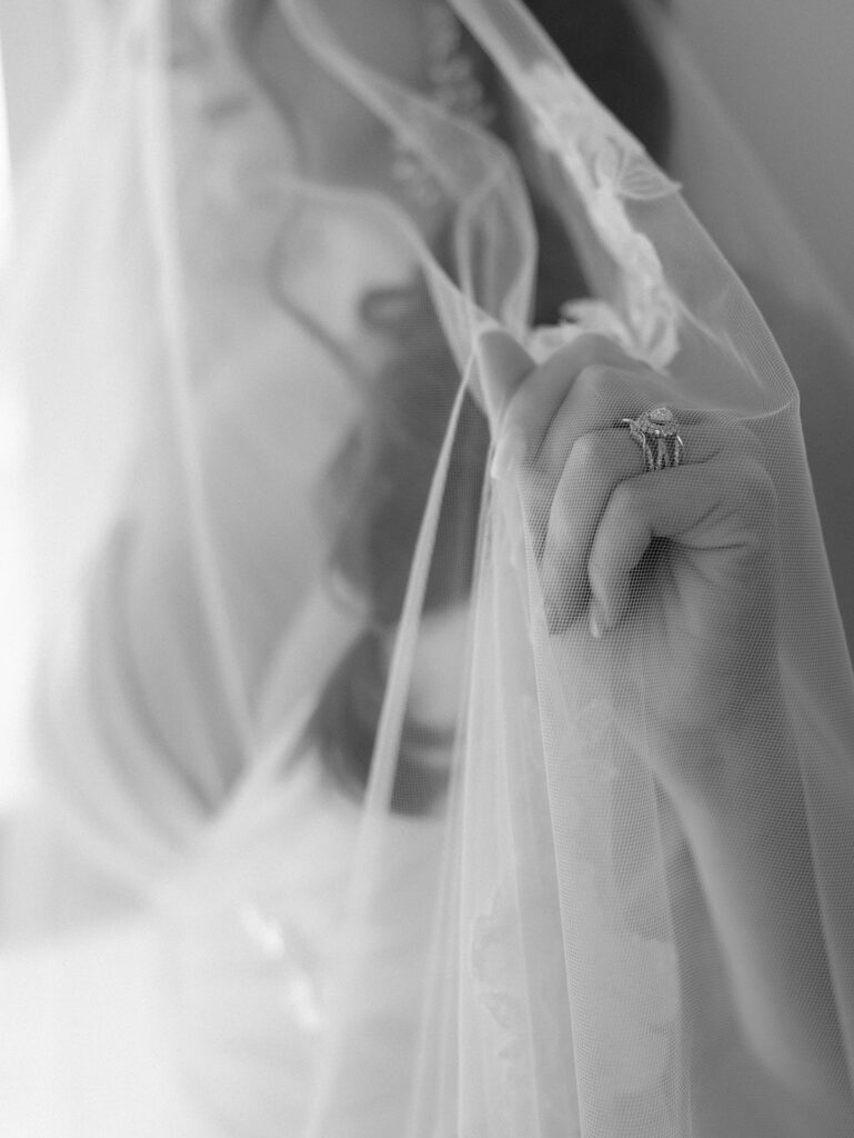 romantic close up portrait of bride under veil showing off her ring