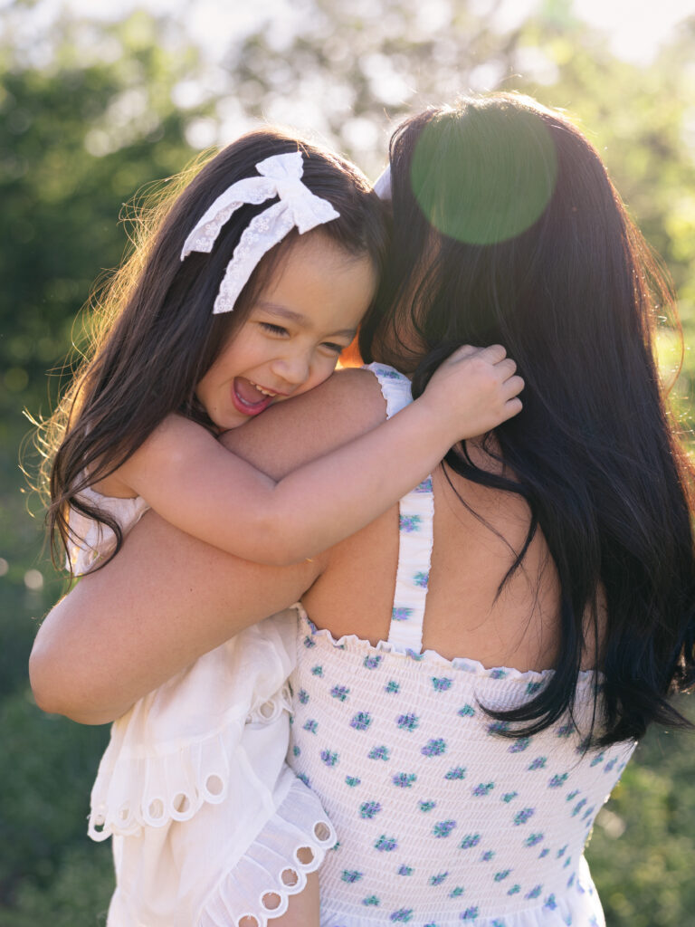 mom holding daughter close with sunbeam coming in